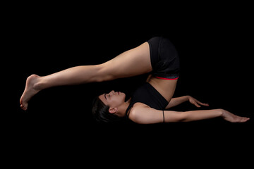 Fototapeta na wymiar Young woman doing fitness exercise training isolated on the black background. Horizontal shot.