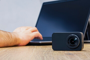Action Camera on the table against the background of a man working at a laptop.