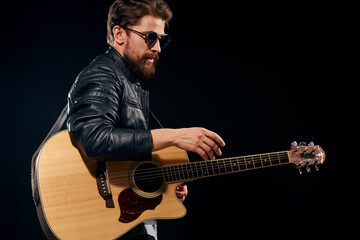 Obraz premium man with a guitar in his hands black leather jacket sunglasses music emotions black background