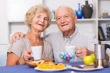 Obraz na płótnie Canvas Portrait of happy mature couple having good time drinking tea in kitchen.