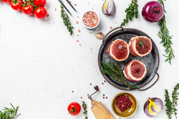 Top of view beef tenderloin steaks wrapped in bacon served on old meat tray on a light background, top view
