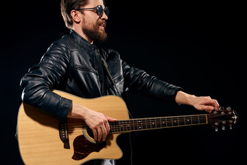 man with a guitar in his hands black leather jacket sunglasses music emotions black background