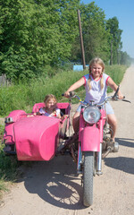  In the village, children sit on a motorcycle with a stroller. 