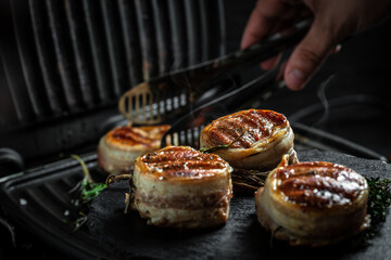 Grilled Fillet Mignon tenderloin meat beef steaks fillet wrapped in bacon. Cooking beef steak on grill by chef hands