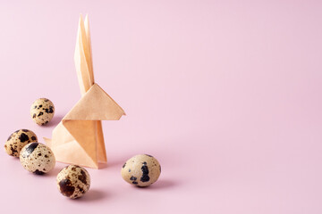 Paper origami bunny, quail eggs on pink background. Minimal modern Easter concept. Bright Easter background, copy space