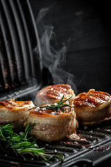 filet Mignon beef tenderloin steak is grilled in a grill. tenderloin steaks wrapped in bacon. ground pepper in a freeze motion