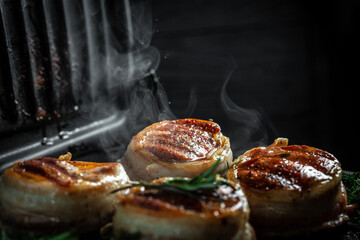 filet Mignon beef tenderloin steak is grilled in a grill. tenderloin steaks wrapped in bacon. ground pepper in a freeze motion