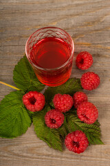 homemade sweet raspberry wine or juice in small glasses with fresh berries on aged wooden table