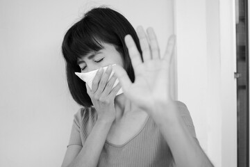 Black and white image of Asian woman have a cold. she is sneezing into handkerchief. sick from virus problem. authentic black hair, skin tan and slim shape. health care concept.