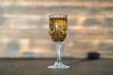 Homemade birch buds tincture in a wine crystal glass on a wooden table background