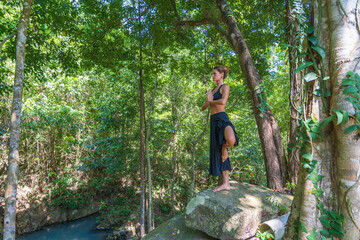 Young caucasian brunette girl is meditating in nature at tropical garden in summer, Thailand