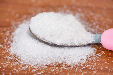Monosodium glutamate on spoon and wooden table background, MSG for food seasoning