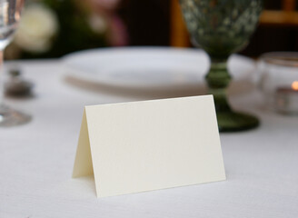 Mockup white blank space card, for Name place, Folded, greeting, invitation on wedding table setting background. with clipping path
