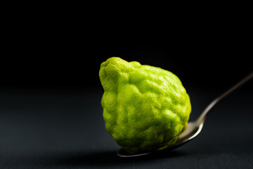 Fresh bergamot fruit on black background with spoon, Organic herbal and food ingredient