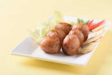 Thai sausage or Isan sausage, grilled fermented rice with minced pork on plate and fresh vegetables