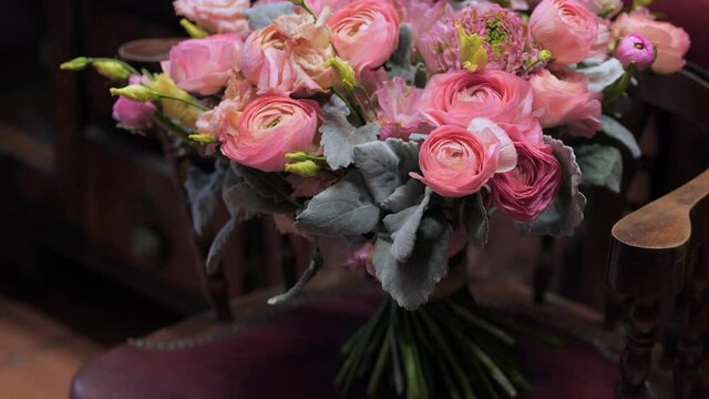 Beautiful bouquet of fresh cut pink and yellow roses on vintage chair in flower shop. Natural floral composition for festive event