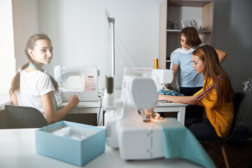 Fototapeta premium Cute female children sewing clothes in workshop