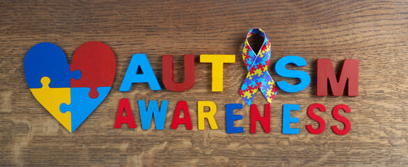 Autism awareness. Autism awareness ribbon, heart and word autism on wooden background background.