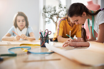 Cute female kids making sewing patterns in workshop