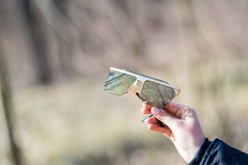 Futuristic Oversized sunglasses model with golden lenses shoot outside in nature in a sunny day closeup . Selective focus. High quality photo