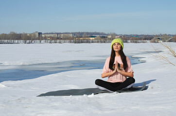 yoga in nature. girl meditates in winter on the river bank