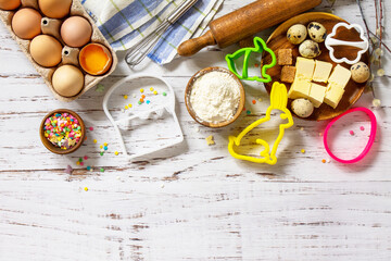 Baking background. Ingredients for Easter festive baking - flour, brown sugar, eggs, butter, confetti on rustic kitchen table. Flat lay. Top view. Copy space.