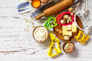 Baking or cooking background frame. Ingredients, kitchen items for Easter festive baking. Kitchen utensils, flour, brown sugar, eggs, butter, confetti on rustic kitchen table. Flat lay. Copy space.