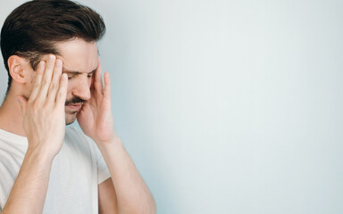 Young man suffering from headache indoors. Close-up, copy space for text. Man holding his head. Depression, fatigue, headache, frustration concept