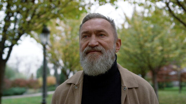Portrait of mature man with long grey beard outdoors. Old man going.