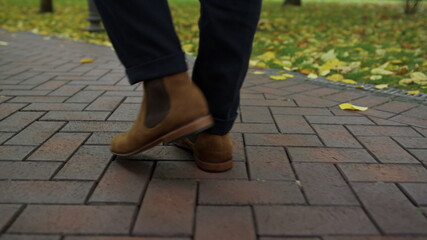 Fototapeta premium Unrecognizable man feet stroling on street. Closeup male boots outdoors. 