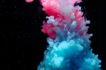 Multi-colored paints in water. Ink swirls underwater. A cloud of collision of bright ink on a black...