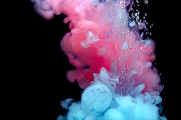 Multi-colored paints in water. Ink swirls underwater. A cloud of collision of bright ink on a black background. Colorful abstract explosion of smoke. Abstract background