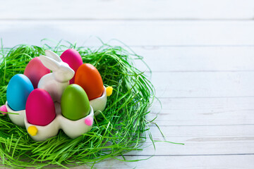Colorful Easter eggs in a nest with green grass on a wooden background. Geometry. The minimal concept of Easter. Top view. An Easter card with a copy of the place for the text.