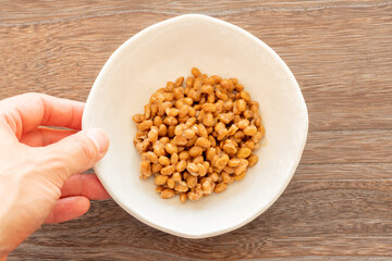 納豆の皿を木製テーブルに置く