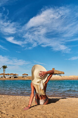 Young fashion woman sitting on the beach shore