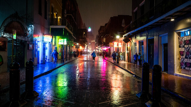 Bourbon Street in new orleans is rain soaked after a heavy spring downpour. Colored lights reflect off the famous street. 