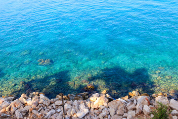 Blue water texture background. Surface of the Mediterranean sea with rocky shore. Top view
