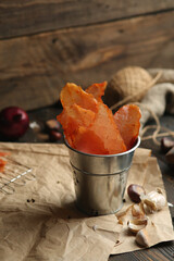 Homemade beef jerky seasoned with garlic, onion, pepper and salt. Jerky in a bucket on a wooden...