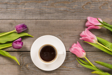 Fototapeta na wymiar fresh pink tulips on gray wooden aged table top, good morning or greetings bouquet with white coffee cup