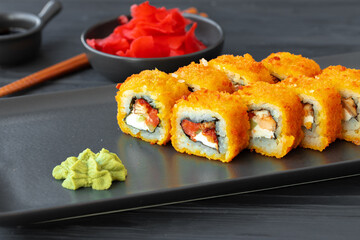 Sushi roll fried in tempura on black plate