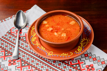 Borscht, Ukrainian beetroot soup in ceramic bowl over traditional Ukrainian tablecloth.