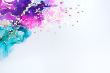 art photography of abstract fluid art painting with alcohol ink blue, purple, pink, gold colors and crystal rhinestones