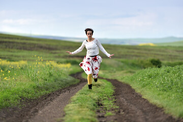 Playful girl in skirt running in canola field in the spring