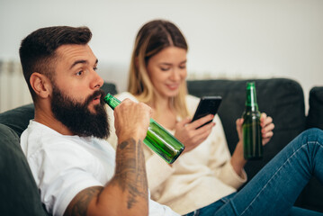 Couple drinking beer and watching television at home