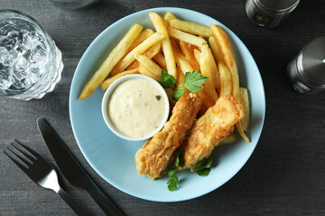 Concept of tasty eating with fried fish and chips on dark textured table
