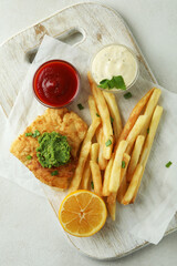 Concept of tasty eating with fried fish and chips on white textured table
