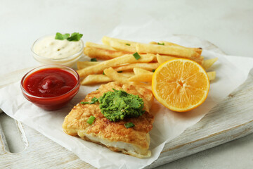 Concept of tasty eating with fried fish and chips on white textured table