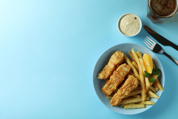 Concept of tasty eating with fried fish and chips, and beer on blue background
