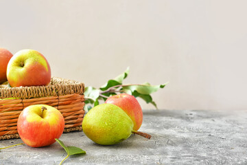 Naklejka na ściany i meble Basket with tasty apple and pear fruits on grey background