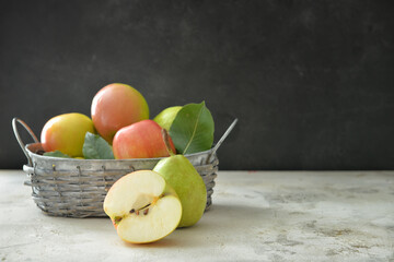 Basket with tasty apple and pear fruits on table